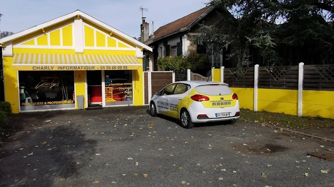 Façade jaune de la boutique Charly Informatique à La Hume, avec la voiture de service devant l’entrée